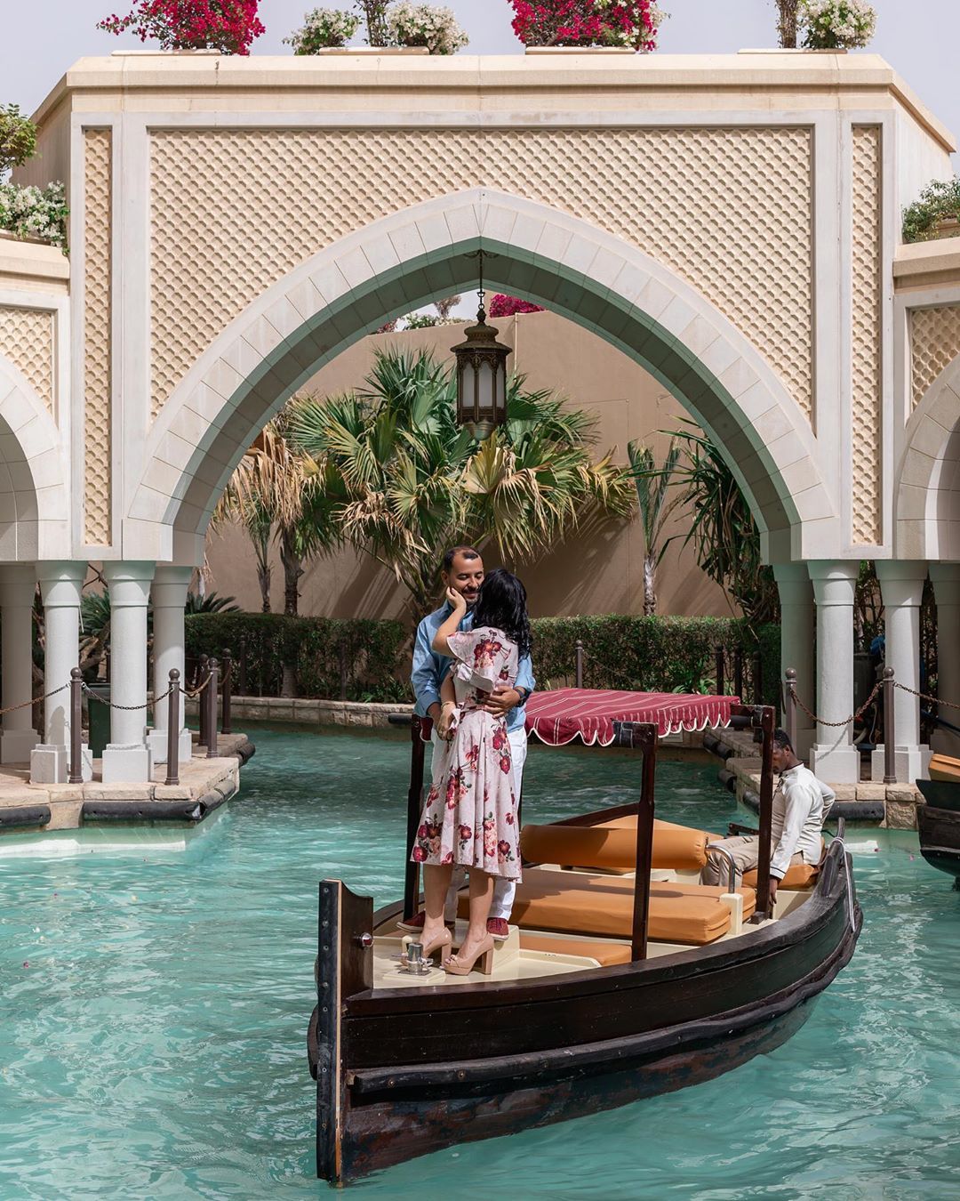 Beautiful couple posing in ambra boat floating across Abu Dhabi artificial channel.