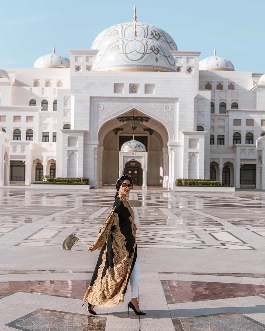 Красивая женщина в элегантном арабском национальном платье прогуливается около дворца в Абу-Даби.