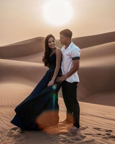 Beautiful young couple posing in Dubai desert at sunset.